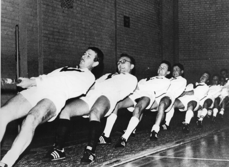 a group of men sitting on top of a basketball court, a black and white photo, dribble, wearing a school soccer uniform, oscar niemeyer, crawling, photographic print