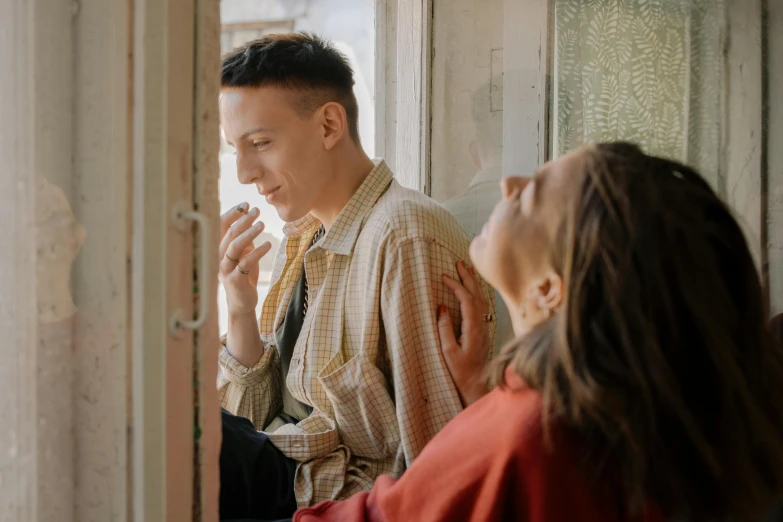 a man and a woman sitting in front of a window, pexels contest winner, antipodeans, holding a cigarette, eleven/millie bobbie brown, leaning on door, color footage