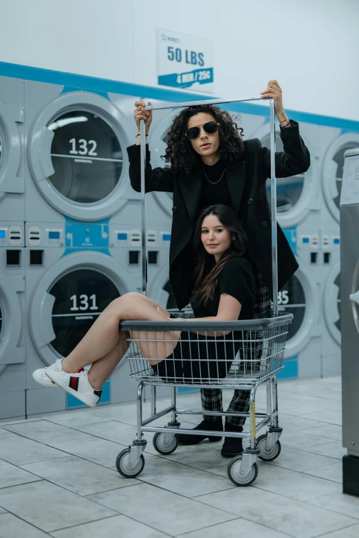 a man and a woman sitting in a shopping cart, pexels contest winner, in a laundry mat, wavy long black hair and glasses, streetwear, washing machine