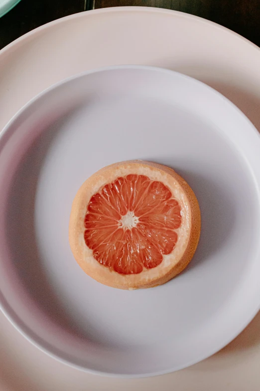 a grapefruit cut in half on a white plate, unsplash, made of glazed, gal gadot china plate, slightly pixelated, soft but grumpy