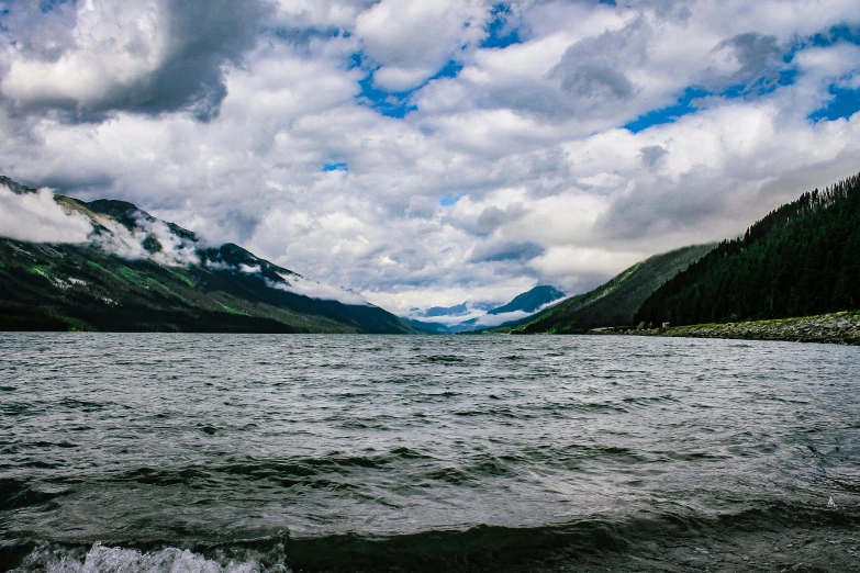 a body of water with mountains in the background, by Hazel Armour, pexels contest winner, hurufiyya, gray clouds, katey truhn, turbulent lake, hd footage