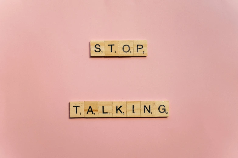 the words stop talking spelled in scrabbles on a pink background, by Sophia Beale, trending on pexels, happening, on a pale background, biological, - 12p, disconnection