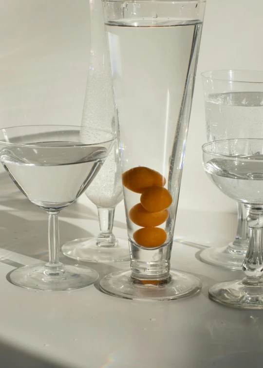 a table topped with glasses of water and oranges, a still life, inspired by Johannes Martini, unsplash, photorealism, modern crystal martini glass, translucent orbs, large tall, small rectangular glasses