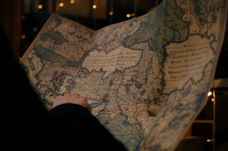 a close up of a person holding a map, by Emma Andijewska, trending on unsplash, renaissance, low lighting, russian, brown, still from film