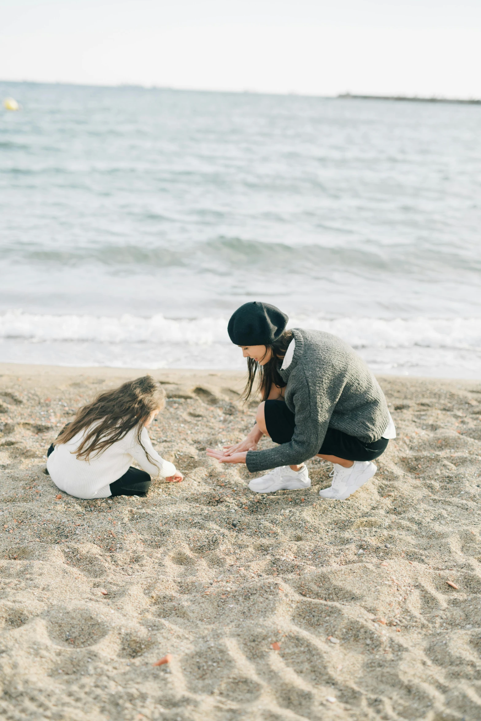 a mother and daughter playing in the sand at the beach, unsplash, minimalism, calmly conversing 8k, boy and girl, kneeling, teenage girl