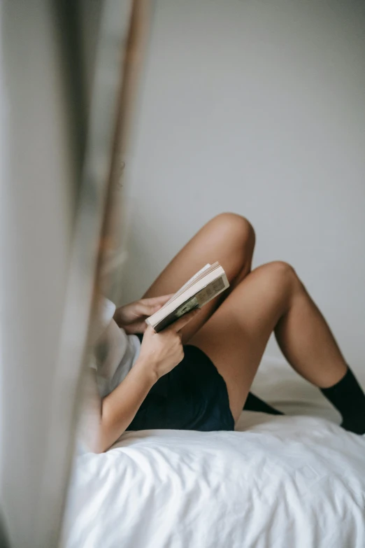 a woman laying on a bed reading a book, by Grace Polit, trending on unsplash, exposed thighs, androgynous, gif, 6 : 3 0 am