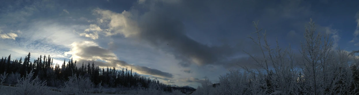 a man riding a snowboard down a snow covered slope, an album cover, pexels contest winner, hurufiyya, with dark clouds in the sky, in an arctic forest, hovering above a lake in yukon, low quality footage