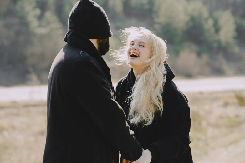 a man and a woman standing next to each other, pexels contest winner, romanticism, she is laughing, elle fanning in a black coat, hairs fly in the wind, youtube thumbnail