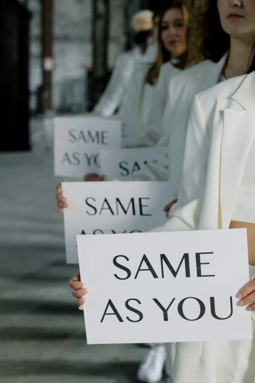 a group of women standing next to each other holding signs, inspired by Vanessa Beecroft, unsplash, teamlab, saws, on the runway, ap news photograph