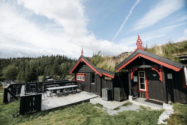 a couple of cabins sitting on top of a lush green hillside, a portrait, by Jesper Knudsen, unsplash, hurufiyya, black and red scheme, barbecue, saloon exterior, nina tryggvadottir