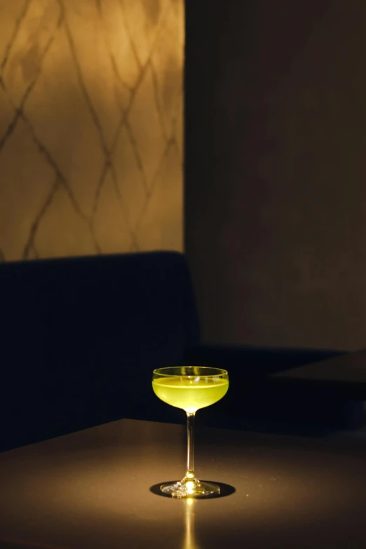 a glass of wine sitting on top of a table, by Ndoc Martini, renaissance, green neon, koju morimoto, lounge, amber