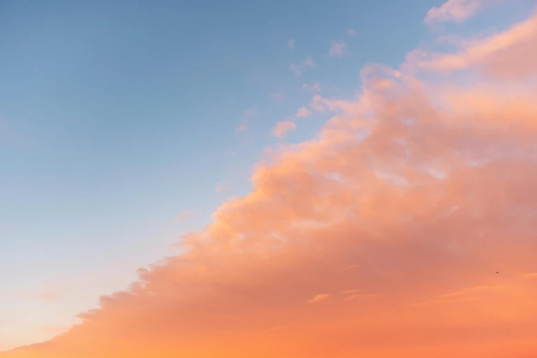 a man riding a surfboard on top of a sandy beach, a picture, unsplash, romanticism, pink clouds in the sky, sunset panorama, golden hour photo, cotton candy clouds