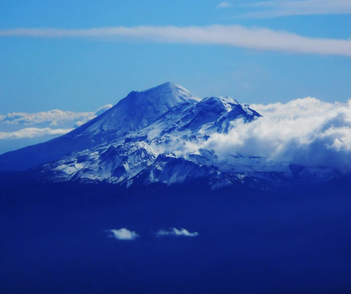 a large mountain covered in snow and clouds, a picture, pexels contest winner, hurufiyya, volcano in the background, blue, cascadia, thumbnail