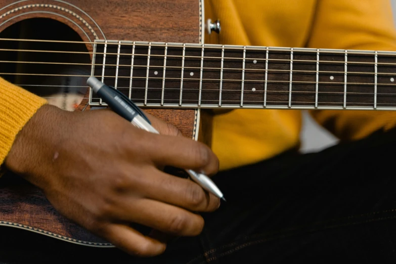 a close up of a person holding a guitar, pexels contest winner, pen and paper, brown, riyahd cassiem, kenne gregoire