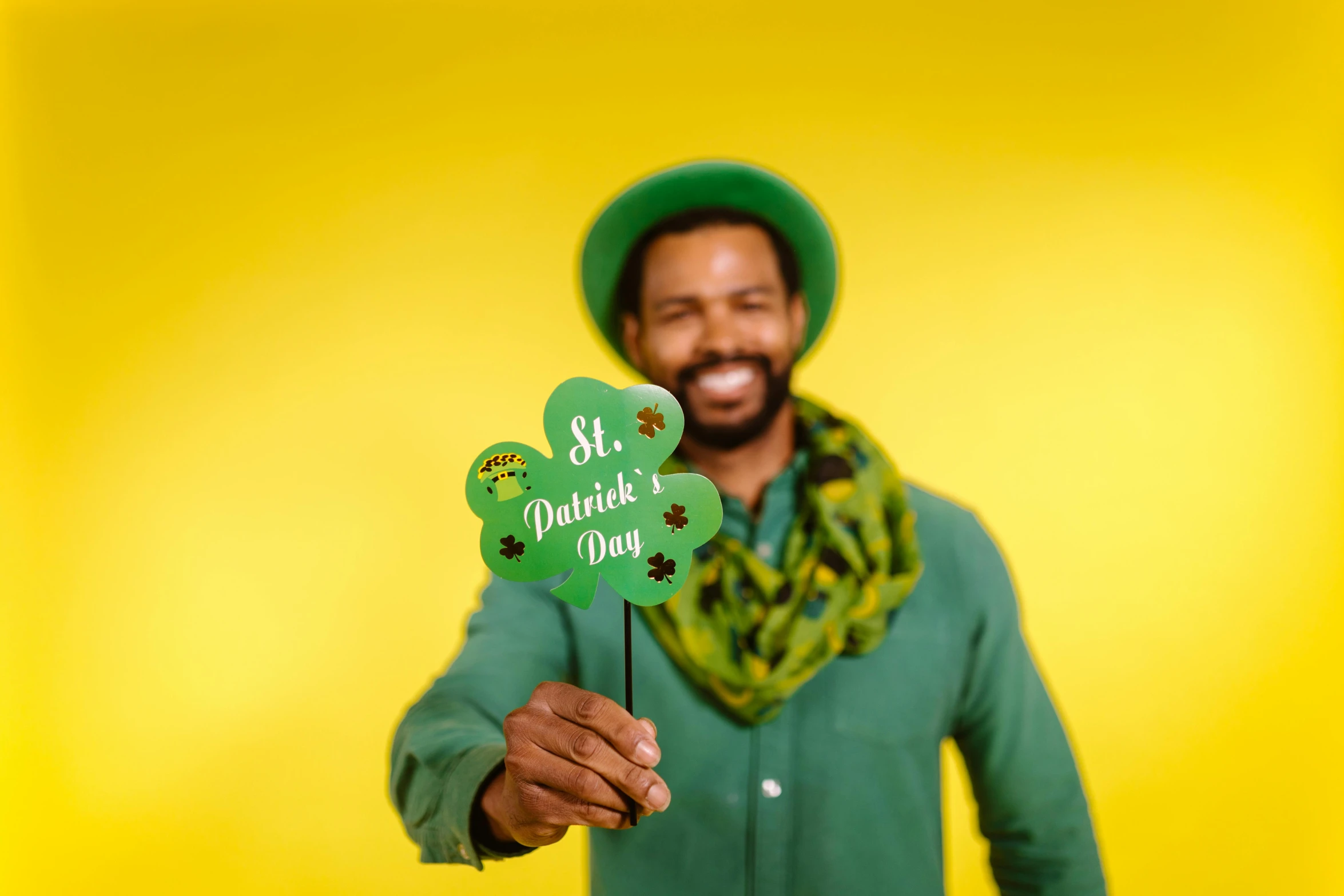 a man in a green shirt holding a four leaf clover, a photo, shutterstock contest winner, photo booth, yellow backdrop, ( ( dark skin ) ), fancy dress