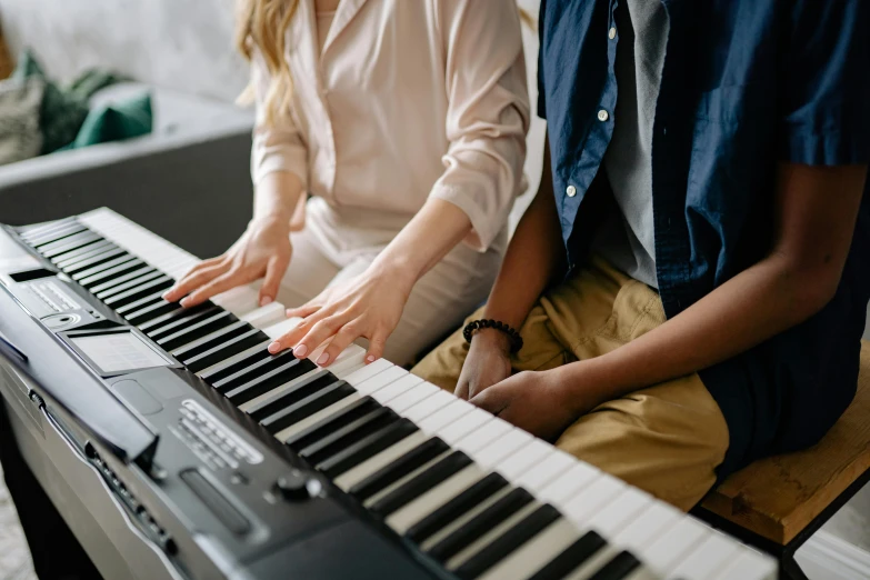 a man and a woman sitting in front of a keyboard, an album cover, trending on pexels, school class, playing piano, professional image, zoomed in