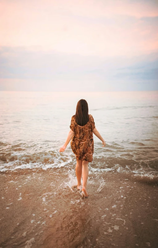 a woman walking into the water at the beach, pexels, renaissance, girl with brown hair, warm hues, teenage girl, 8k octan photo