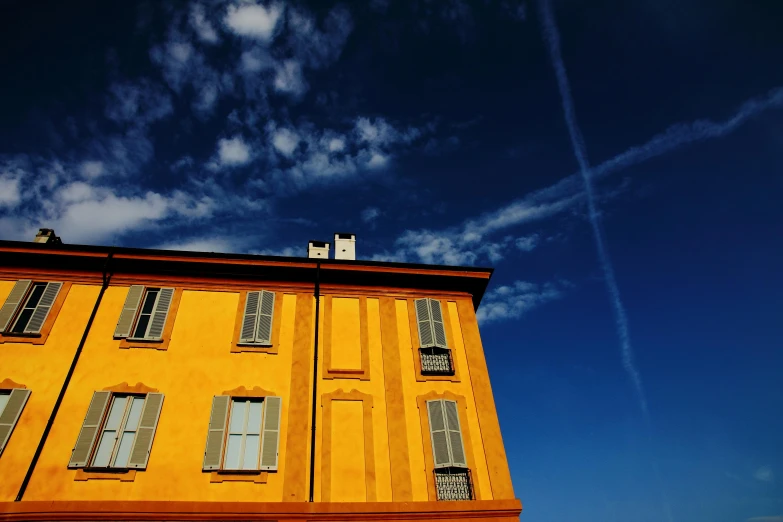 a tall yellow building sitting under a blue sky, pexels contest winner, art photography, italy, dark blue + dark orange, dorne, profile image