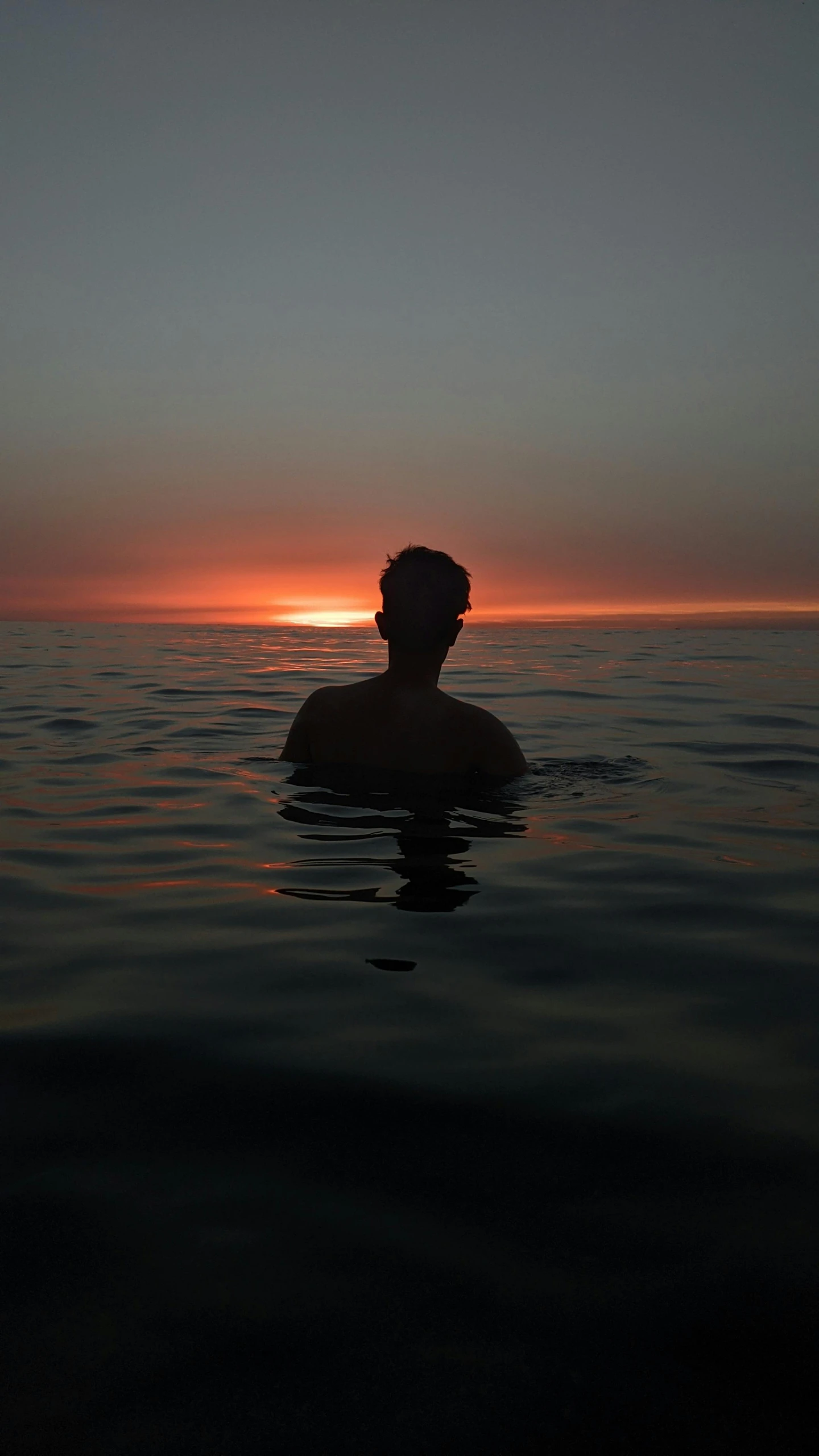 a man swimming in the ocean at sunset, an album cover, unsplash, back lit, single portrait, 8k octan photo