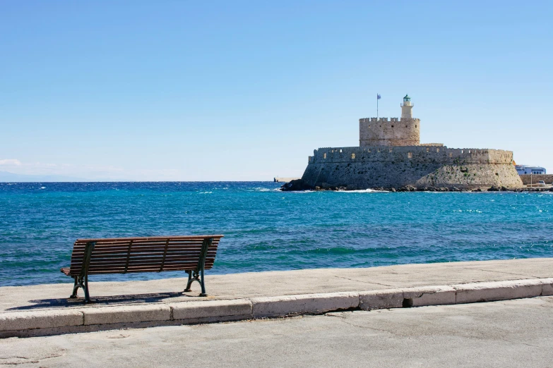 a bench sitting on the side of a road next to the ocean, pexels contest winner, neoclassicism, city walls, colossus of rhodes, square, blue