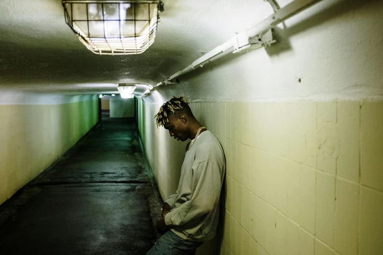 a man leaning against a wall in a tunnel, an album cover, inspired by Elsa Bleda, pexels contest winner, xxxtentacion, detention centre, profile image, upset