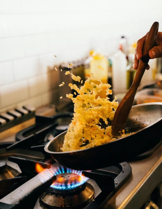a person cooking food in a frying pan on a stove, intricate pasta waves, yellow fur explodes, promo image, onions