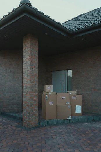 a brick building with boxes in front of it, by Karel Dujardin, unsplash, low quality footage, promo image, entrance, full body image