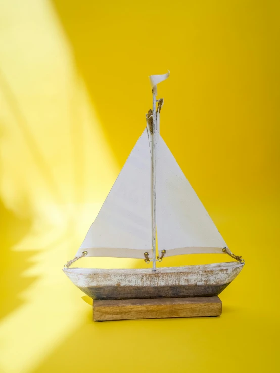 a wooden model of a sailboat on a yellow background, unsplash, new sculpture, whitewashed housed, on a candle holder, full product shot, front shot