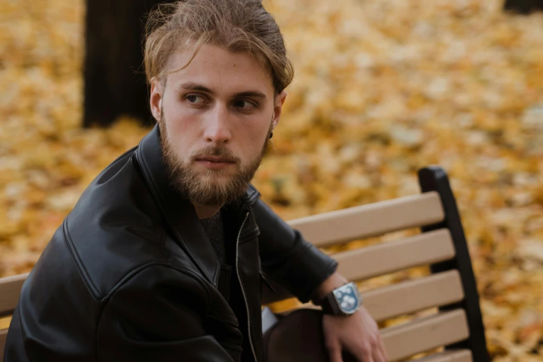 a man sitting on top of a wooden bench, a portrait, trending on pexels, wearing samcrow leather jacket, wearing a watch, avatar image, autumn season