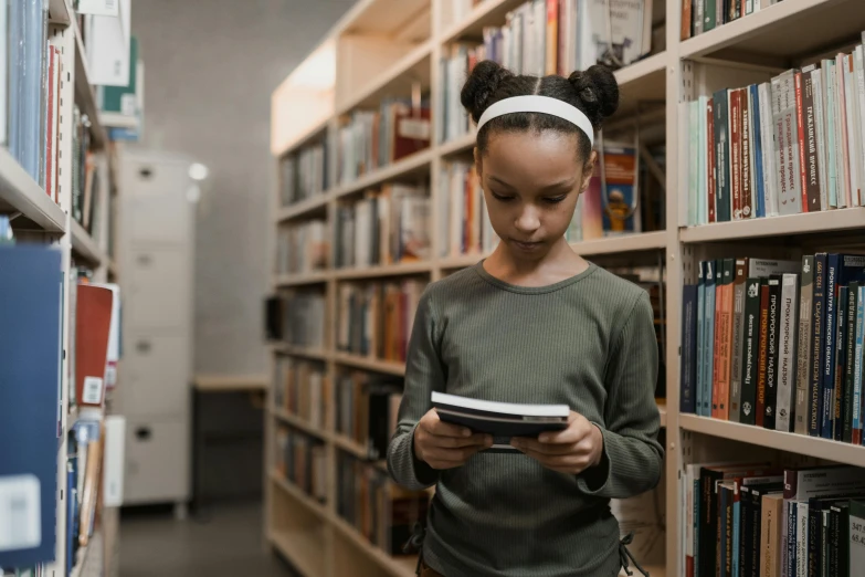 a young girl reading a book in a library, pexels contest winner, mobile learning app prototype, girl standing, quiet beauty, lost in code