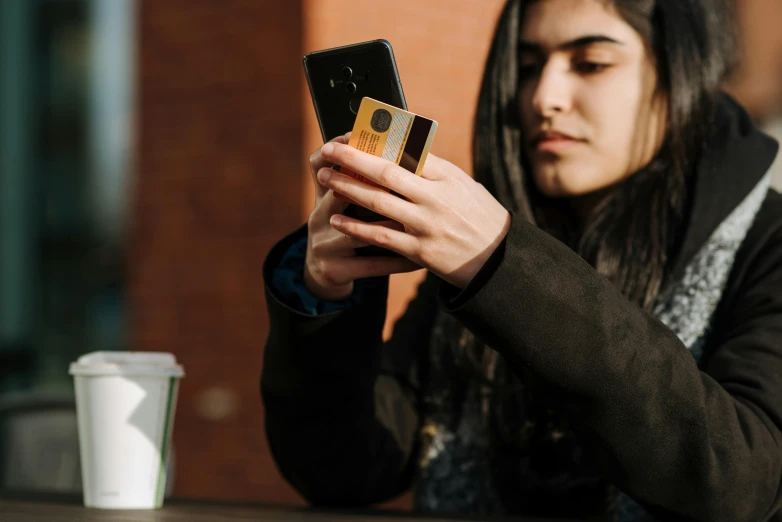 a woman sitting at a table looking at her cell phone, a picture, trending on pexels, renaissance, holding ace card, avatar image, shot from below, holding a wood piece