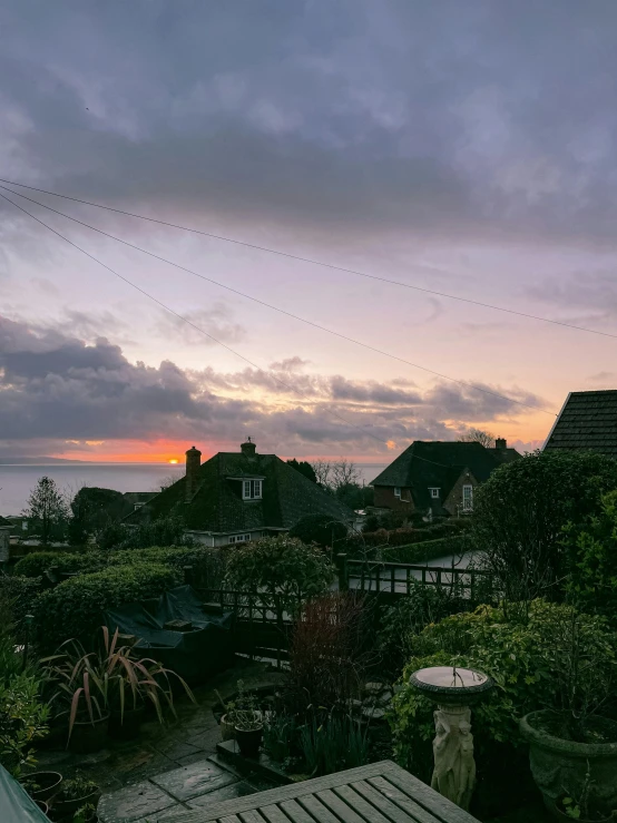 a wooden table sitting on top of a wooden deck, by Matthew Smith, unsplash, happening, hazy sunset with dramatic clouds, sunlight and whimsical houses, seaview, overcast dusk