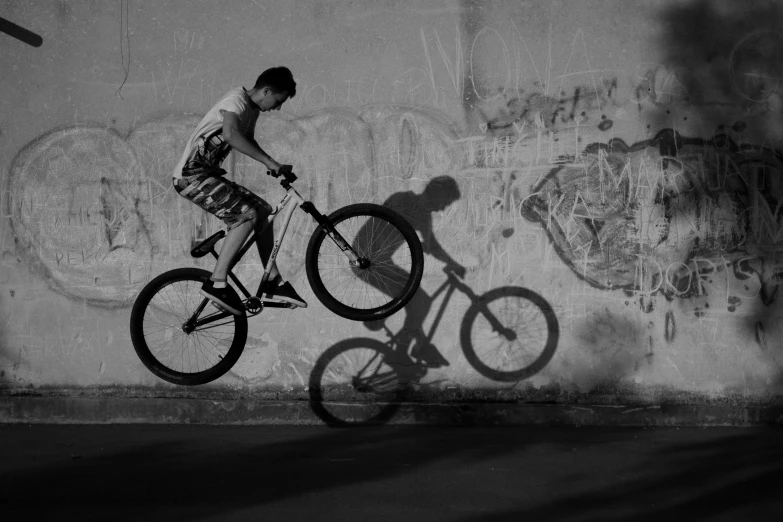 a man riding a bike up the side of a wall, a black and white photo, pexels contest winner, kid, performing, 15081959 21121991 01012000 4k, ::