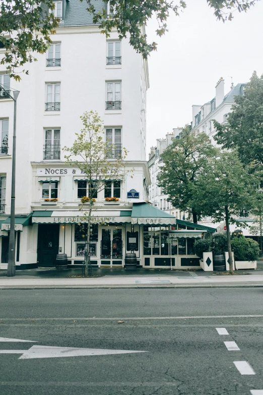 a large white building sitting on the side of a road, a photo, unsplash, paris school, local bar, square, 8 k ”, wide screenshot