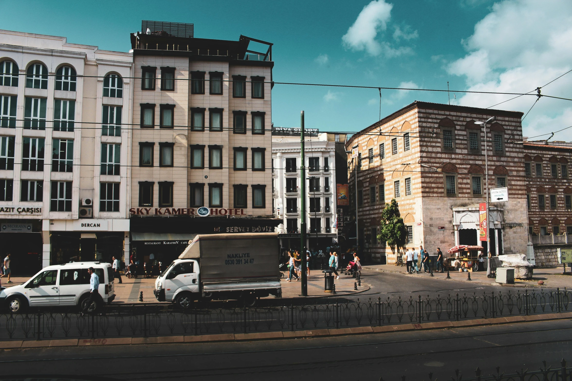 a white van driving down a street next to tall buildings, a photo, by Emma Andijewska, pexels contest winner, renaissance, fallout style istanbul, standing on street corner, panoramic, berghain