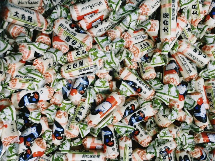 a pile of japanese candy sitting on top of a table, a picture, inspired by Weiwei, pexels, mingei, with white kanji insignias, disposable film, 256x256, green