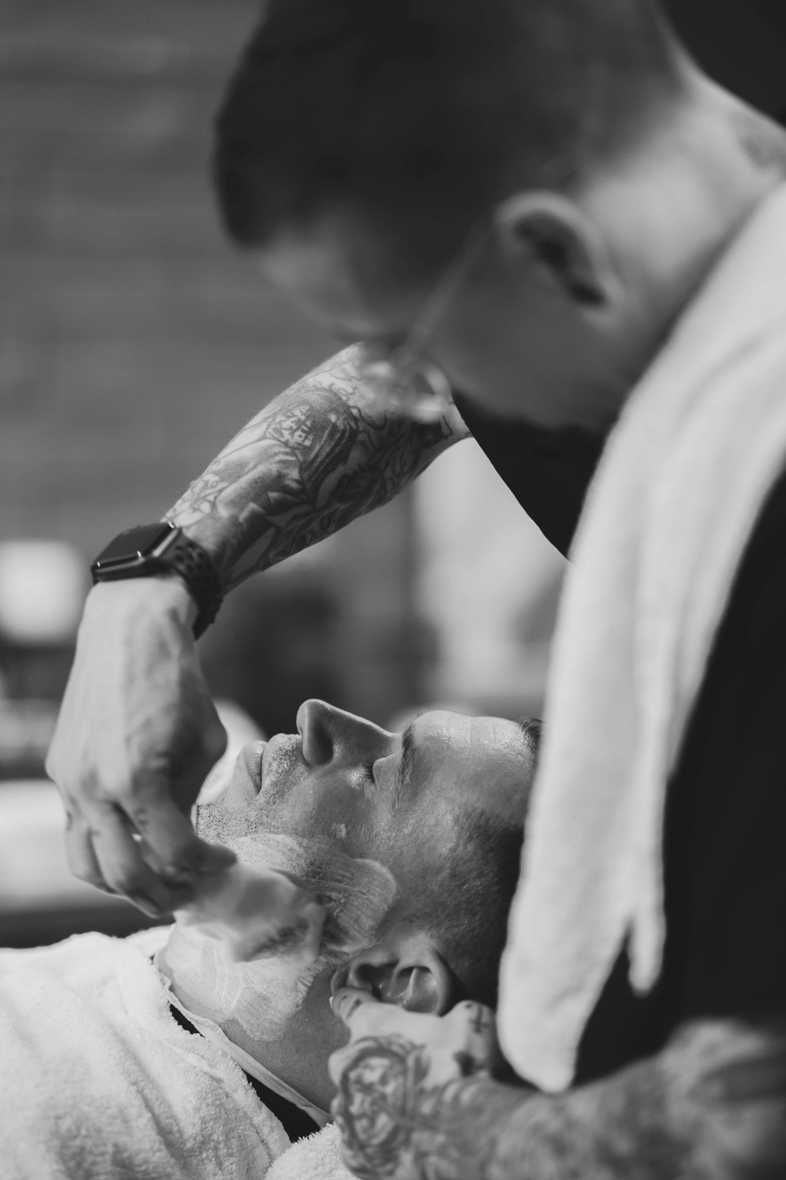 a man getting a haircut at a barber shop, a black and white photo, by Adam Marczyński, pexels contest winner, shaved face, apothecary, detailed body and face, tattooed