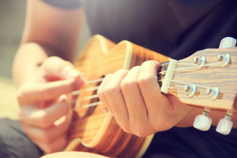 a close up of a person playing a guitar, by Dan Content, shutterstock, hurufiyya, ukulele, slightly sunny, lachlan bailey, from the elbow