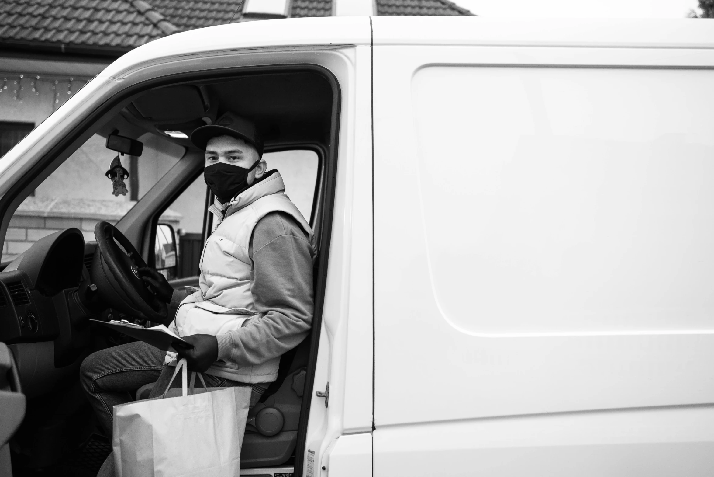 a man sitting in the driver's seat of a van, by Adam Marczyński, wearing mask, avatar image, inspect in inventory image, bw photo