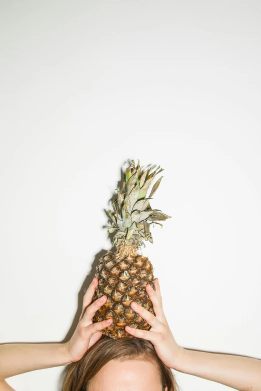 a woman with a pineapple on her head, an album cover, inspired by Elsa Bleda, trending on unsplash, minimalism, hands, digitally enhanced, vegetable, low quality photo