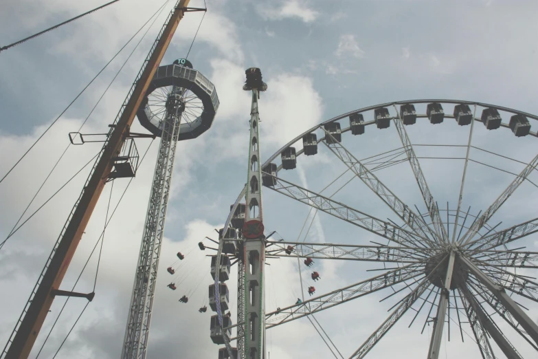 a ferris wheel and a ferris wheel on a cloudy day, a photo, pexels contest winner, aestheticism, sitting in a crane, summer festival in background, grey, high above the ground