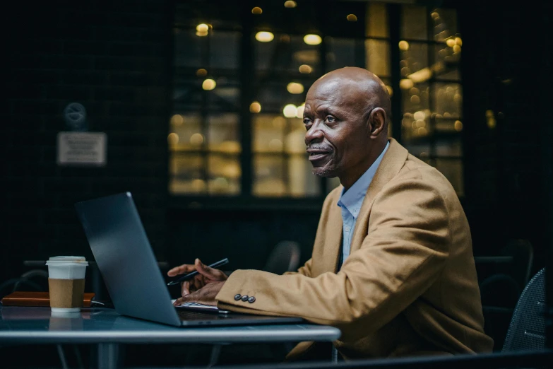 a man sitting at a table working on a laptop, a portrait, by Jesper Knudsen, pexels contest winner, samuel jackson, high quality screenshot, 15081959 21121991 01012000 4k, elegantly dressed