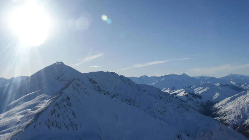 a person standing on top of a snow covered mountain, in the sun, clear blue skies, overview, snowcrash