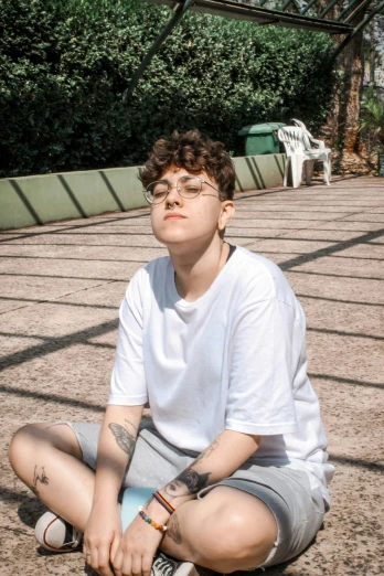 a man sitting on the ground with a skateboard, an album cover, inspired by Ion Andreescu, pexels contest winner, realism, dressed in a white t-shirt, andy milonakis, attractive androgynous humanoid, in sao paulo
