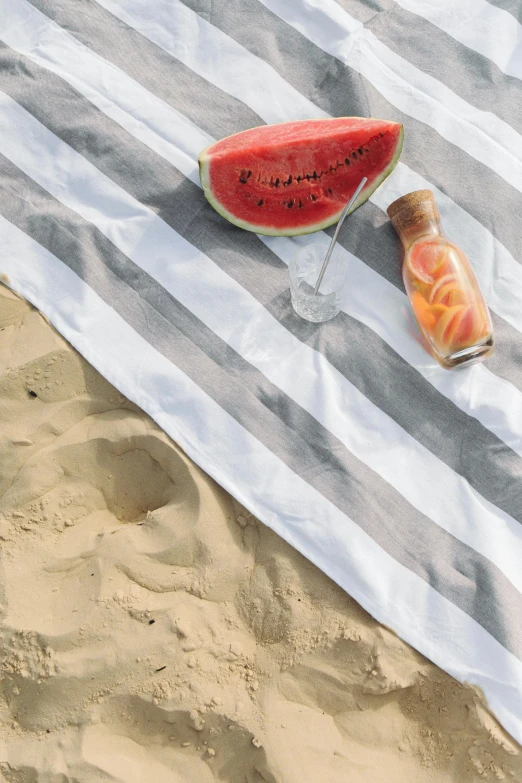 a slice of watermelon sitting on top of a beach towel, charcoal and champagne, sand dune, water bottles, striped