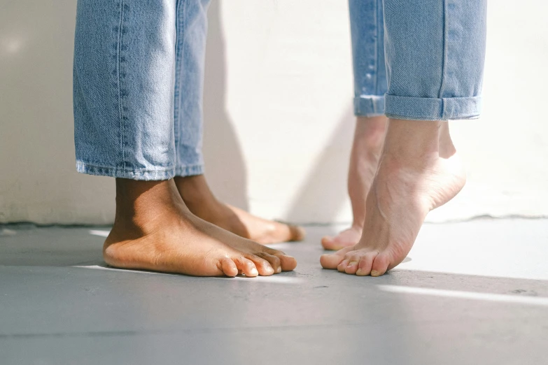 a couple of feet standing next to each other, by Nina Hamnett, trending on pexels, hyperrealism, varying ethnicities, soft skin, sunny light, blue jeans