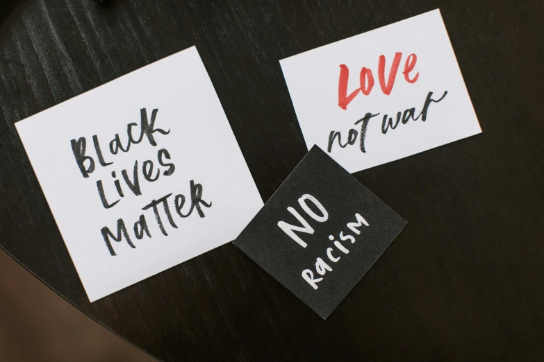 a couple of stickers sitting on top of a table, a black and white photo, by Arabella Rankin, trending on unsplash, private press, protest, black and brown colors, 3 - piece, on a white background