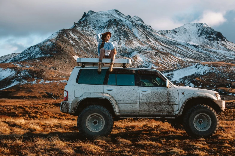 a man standing on top of a white suv, pexels contest winner, girl standing on mountain, 🦩🪐🐞👩🏻🦳, rusty vehicles, avatar image