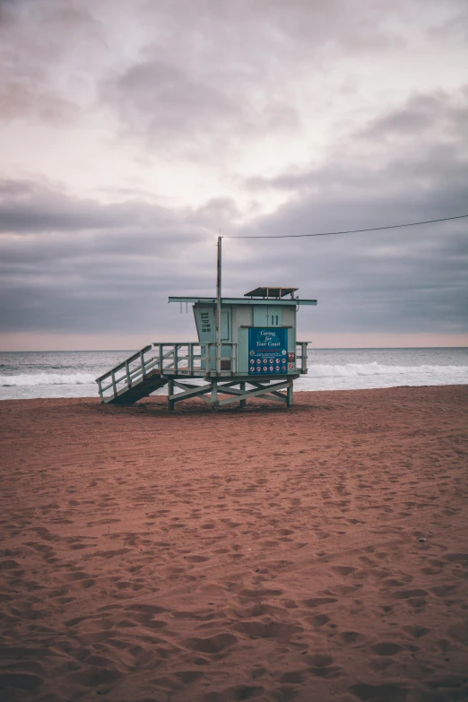 a lifeguard tower sitting on top of a sandy beach, a photo, by Austin English, gloomy colors, square, los angelos, a wooden