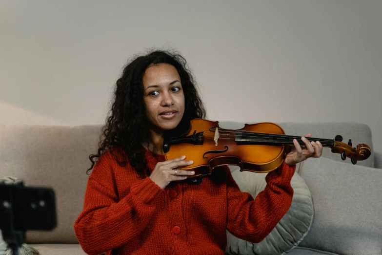 a woman sitting on a couch holding a violin, pexels contest winner, hurufiyya, avatar image, mixed race, profile image, half body photo